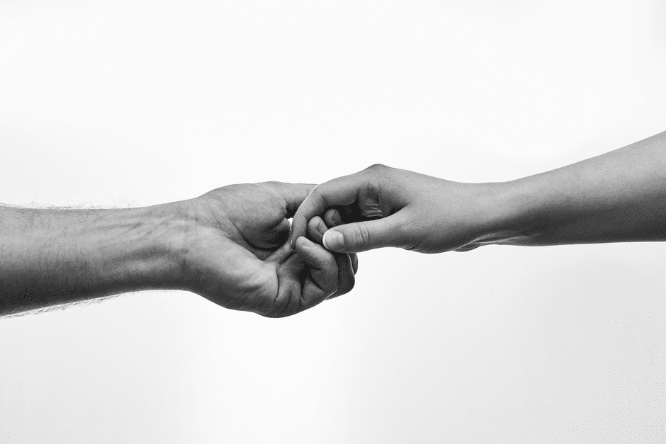 Black and white photo of two hands connecting, symbolizing unity and support.